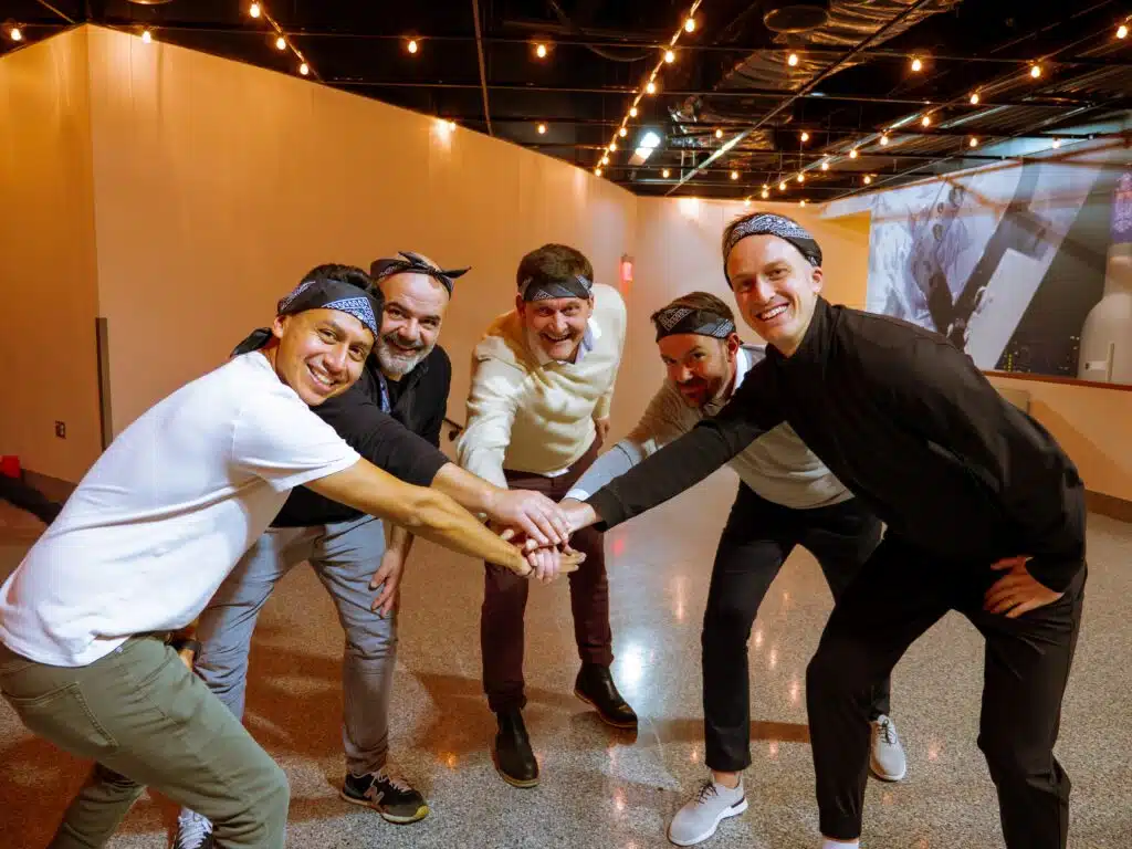 Group of men huddle with hands in the middle