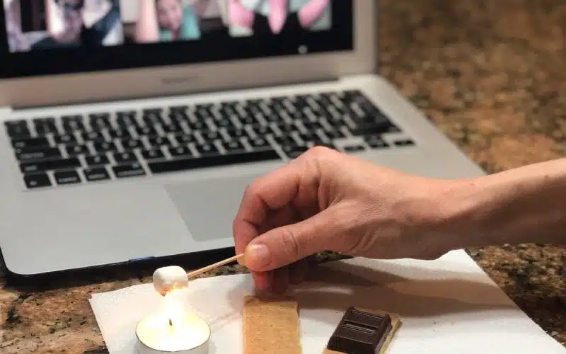 A hand roasting a tiny marshmallow over a candle.